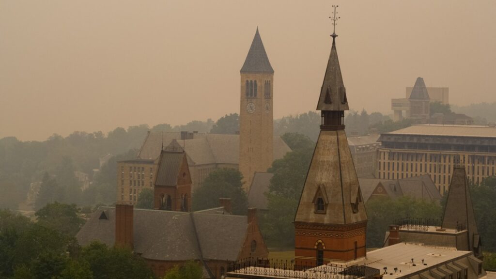Smoke from wildfires burning in Canada shroud the Sage Hall tower, foreground, and McGraw Tower on June 7. On a clear day, Cayuga Lake would be visible. Wildfires can affect human health hundreds of miles away in distant places, professor Oliver Gao said in a recent study. (Jason Koski/Cornell University)
