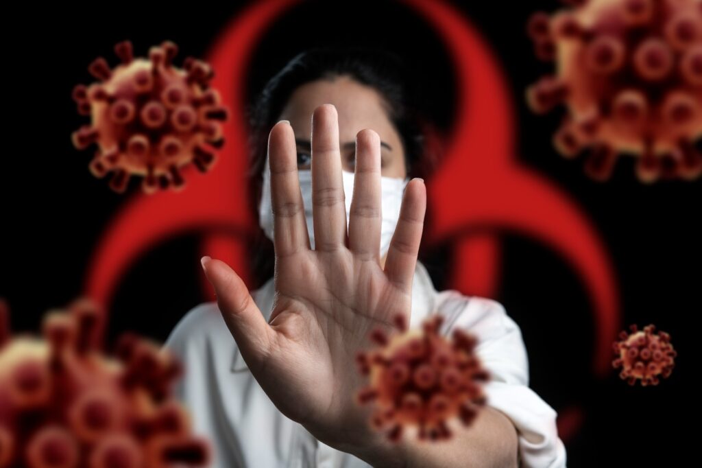 Illustration of health worker holding hand up in front of infectious microbes