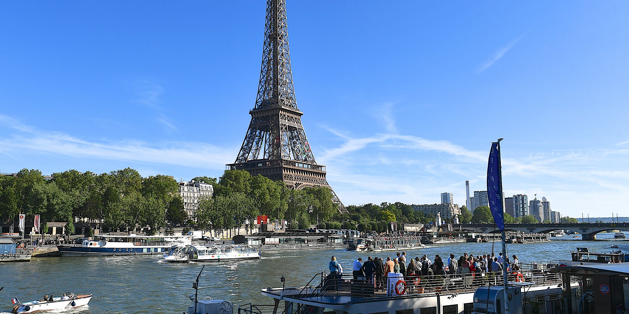 View of the Eiffel Tower with the Olympics rings from the other bank of the Seine river with boats at the docks and in the water, Paris, France. (iStock)