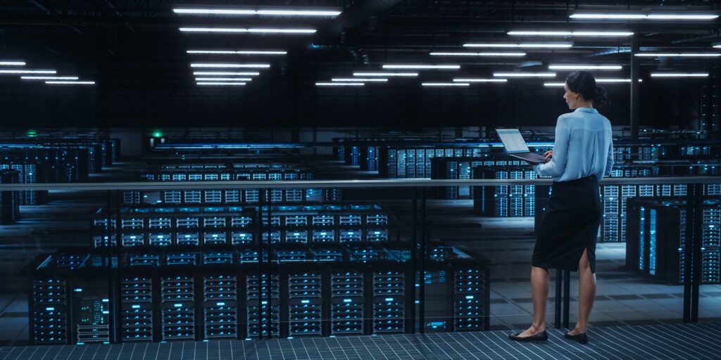 Data center engineer using laptop in server farm cloud