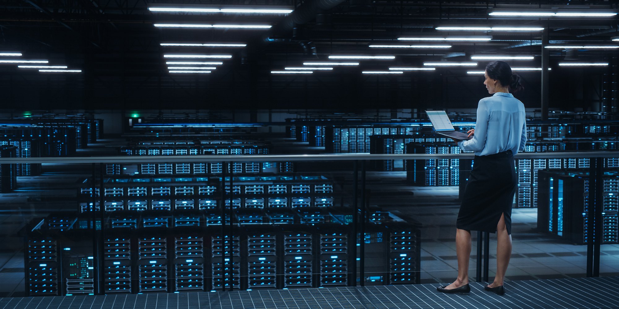 Data center engineer using laptop in server farm cloud