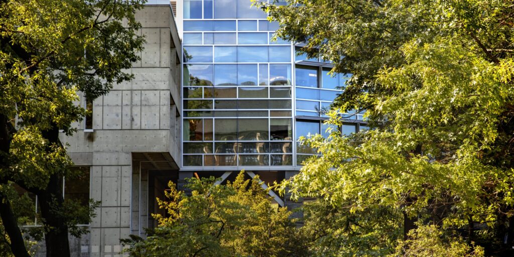 Cornell Health building surrounded by the green leaves of summer.