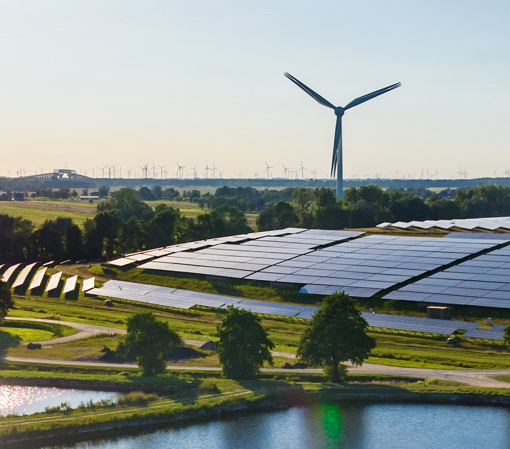 Solar panels and wind turbines near a pond