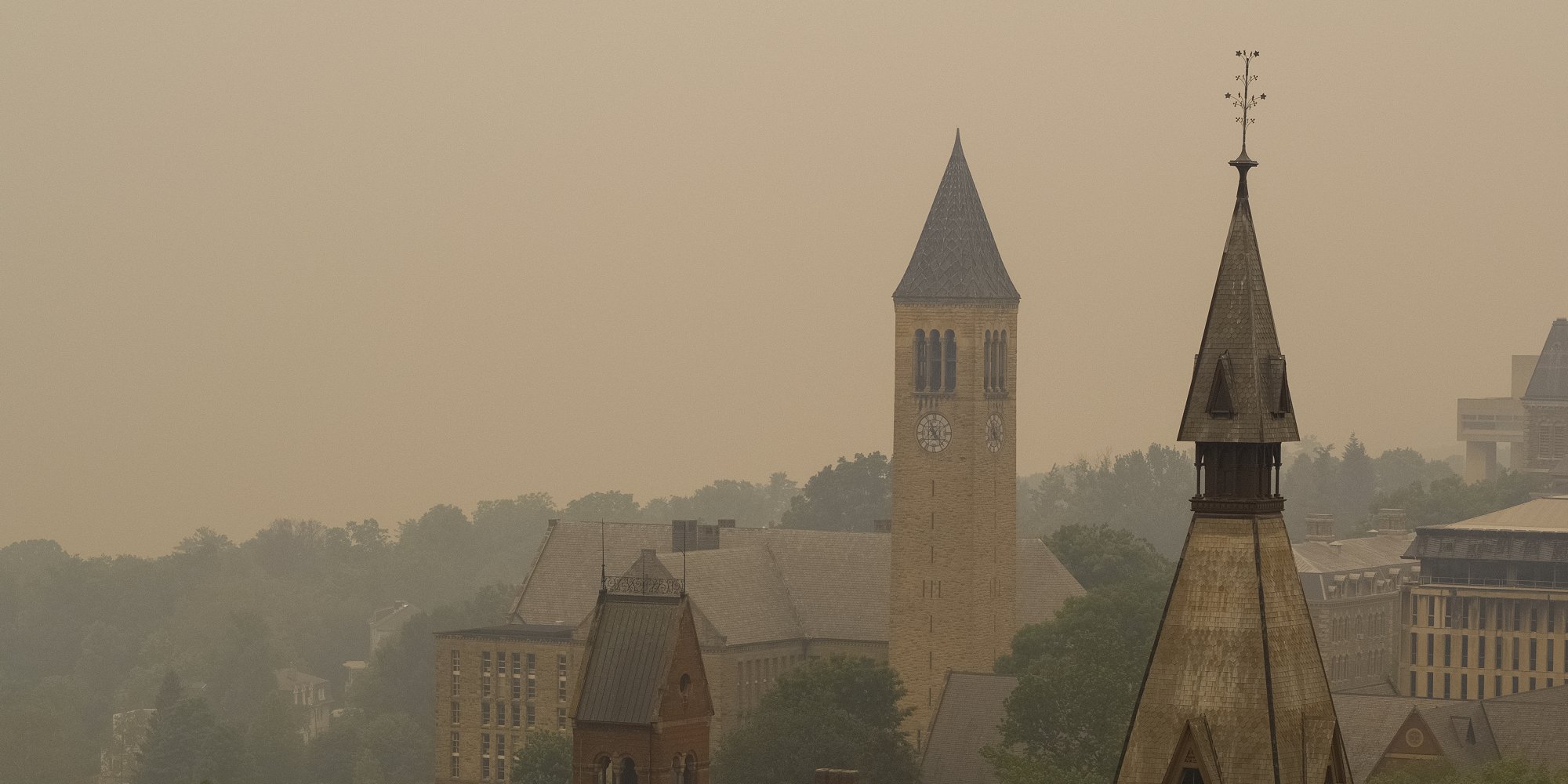 Smoke from wildfires burning in Canada shroud the Sage Hall tower, foreground, and McGraw Tower on June 7. On a clear day, Cayuga Lake would be visible. Wildfires can affect human health hundreds of miles away in distant places, professor Oliver Gao said in a recent study. (Jason Koski/Cornell University)